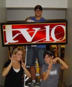 Students help install a sign with TV-10s new logo.